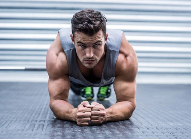 muscular man in tank top doing planks at the gym