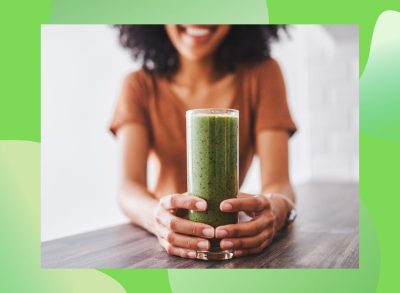 woman holding a glass of smoothie on a green background