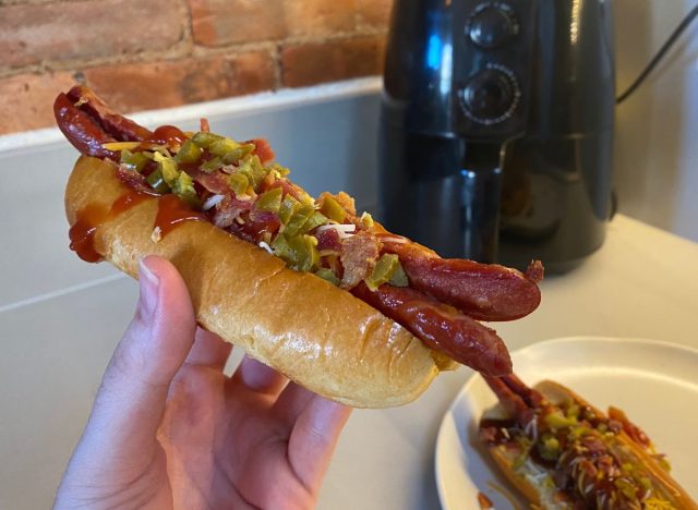 holding a hot dog in a bun with toppings