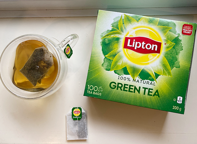 a mug of green tea next to a lipton box 