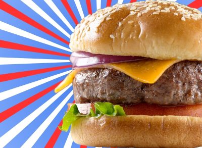 A closeup of a cheeseburger set against a patriotic red, white, and blue background