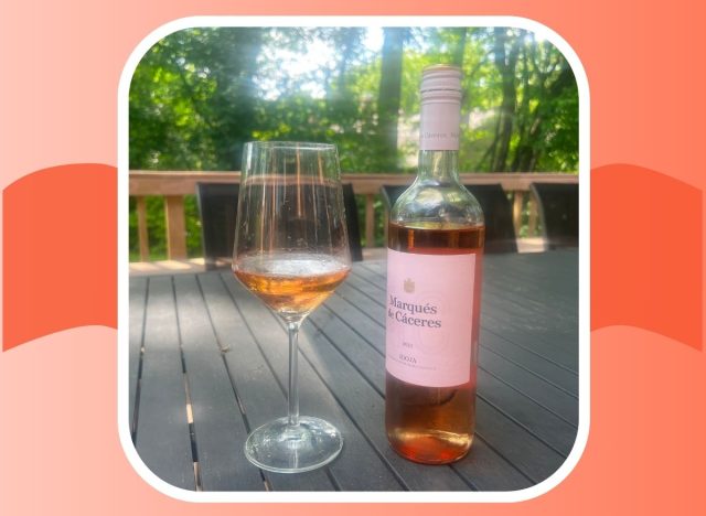 a bottle and glass of marques de caceres rose on an outdoor table 