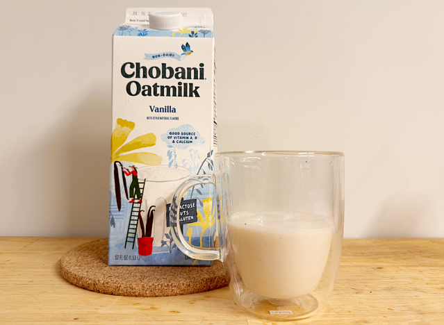 a container of chobani vanilla oat milk next to a glass