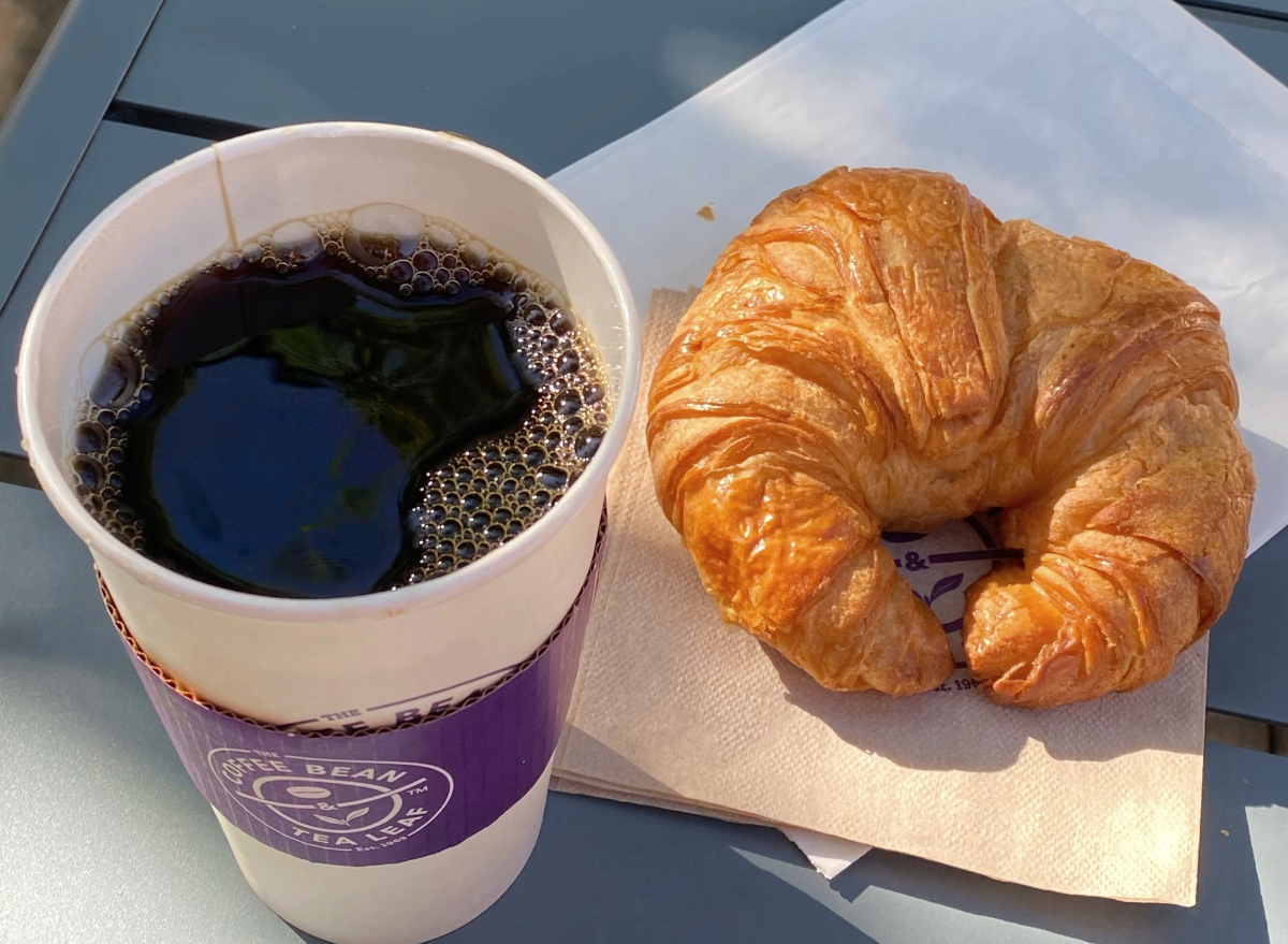the coffee bean and tea leaf cup of coffee and croissant on a table