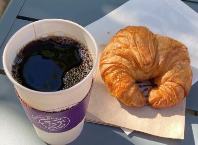 the coffee bean and tea leaf cup of coffee and croissant on a table