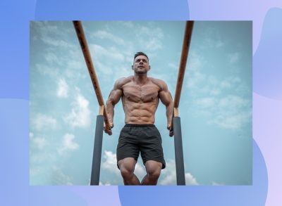 fit, muscular man doing bar dips outside under blue sky