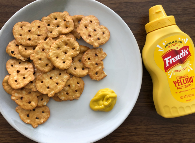 a bottle of mustard next to a plate with pretzels 
