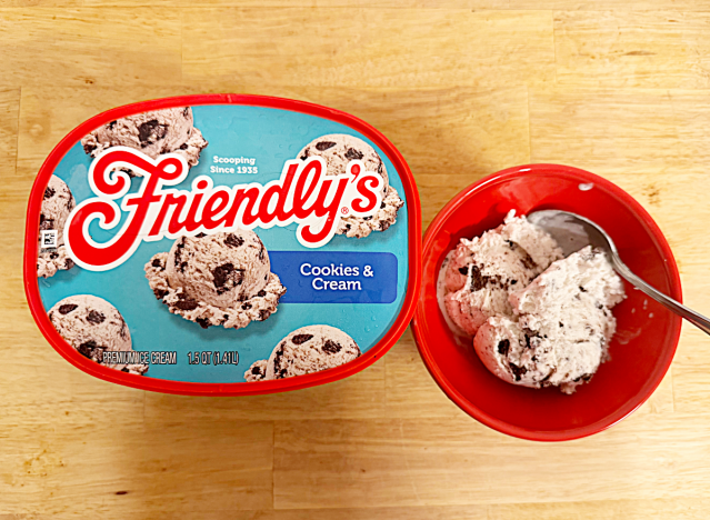 a container of friendlys cookies and cream next to a bowl of ice cream 