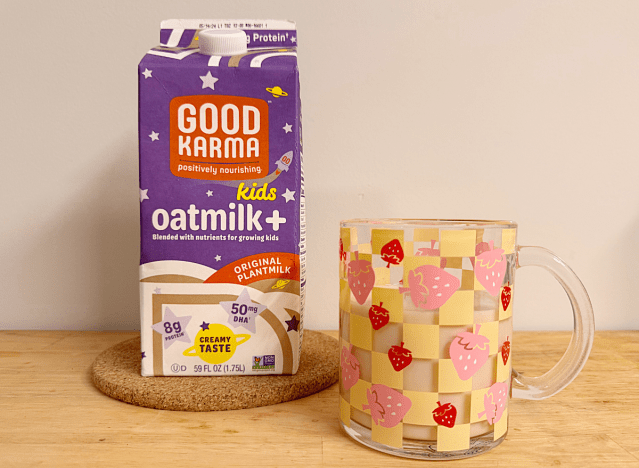 a container of good karma oat milk next to a strawberry printed mug