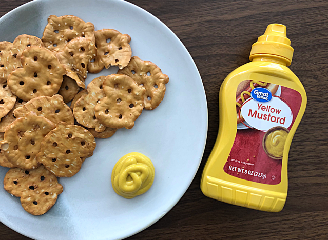 a bottle of great value mustard next to a plate of pretzels 