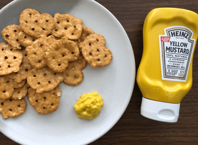 a bottle of heinz mustard next to a plate of pretzels 