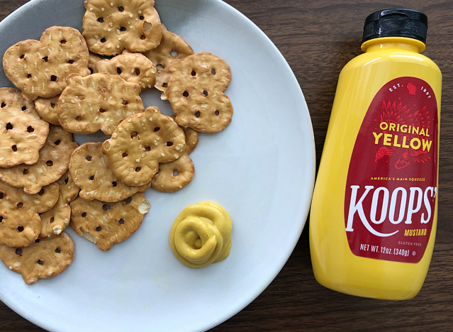 a bottle of koops mustard next to a plate of pretzels 