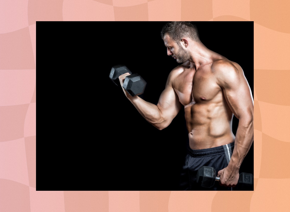 muscular, shirtless man doing bicep curls in front of black backdrop