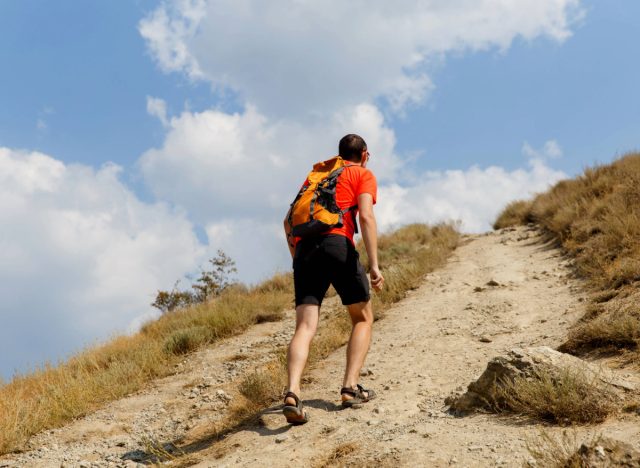 man rucking uphill on hiking path on sunny day