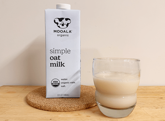 a container of mooala oat milk next to a glass
