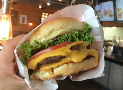 person holding bugerfi cheeseburger