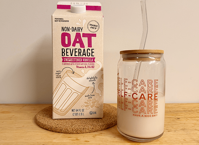 a container of trader joe's oat milk next to a glass cup