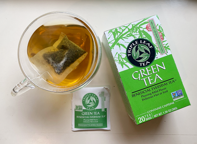 a mug of triple leaf green tea next to box 