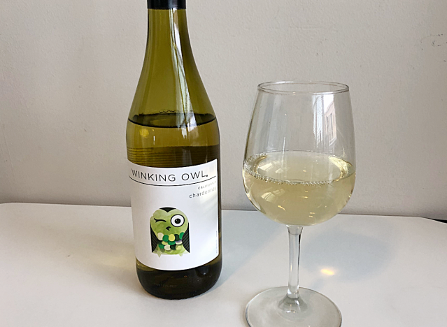 a bottle of chardonnay next to a glass of white wine 