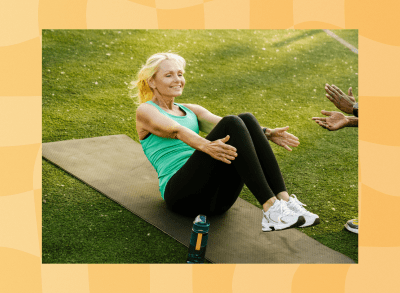 mature blonde woman doing sit-ups on yoga mat outdoors on turf