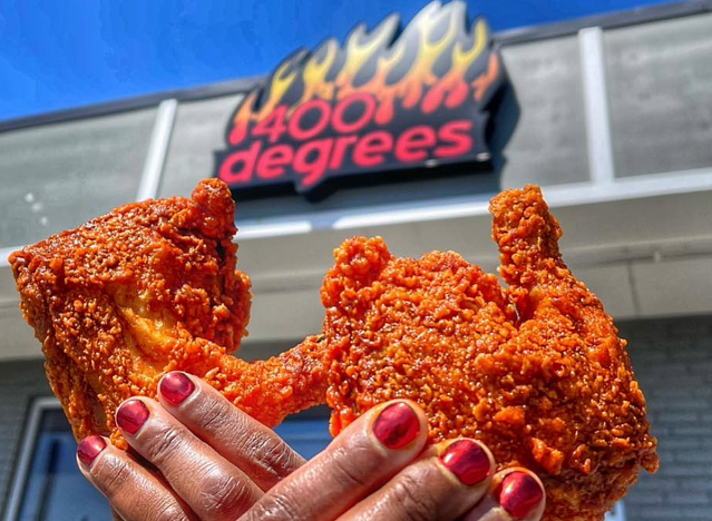 hands holding hot chicken with 400 degrees sign in background