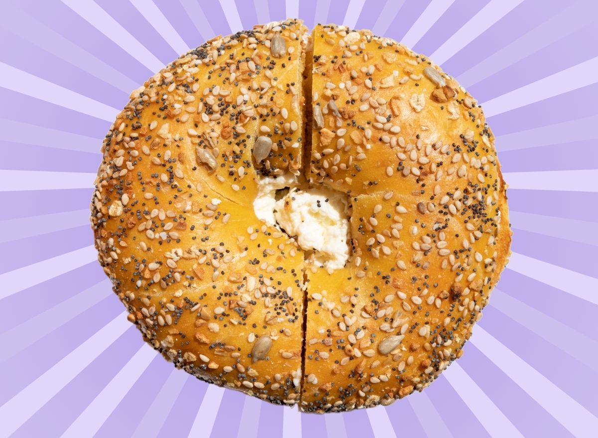 An everything bagel set against a vibrant purple background