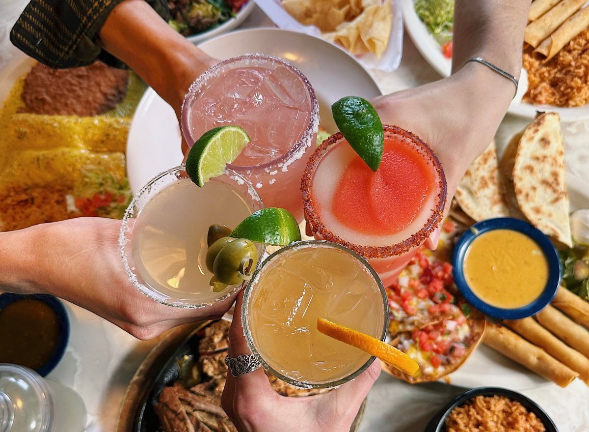 Chuy's customers clinking drink glasses over table of food