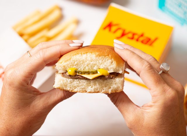 A pair of womanly hands holding an Original Krystal beef slider