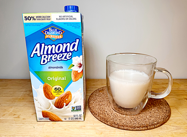 a container of almond breeze almond milk next to a glass of it 