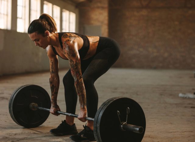 fit, muscular woman doing barbell deadlift exercise
