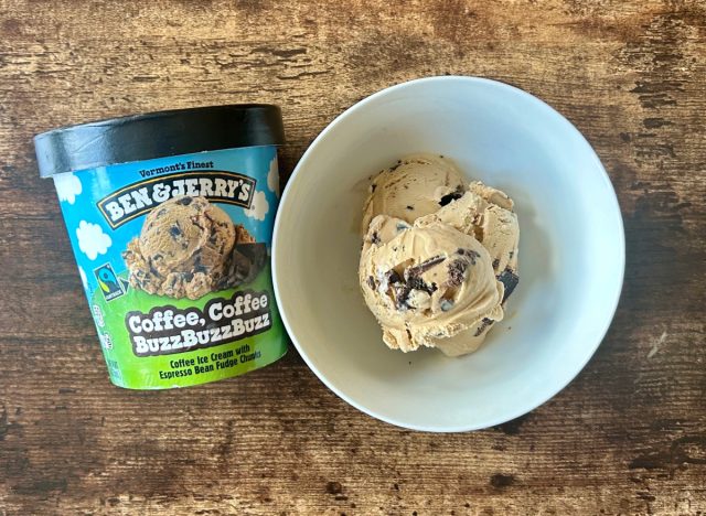 a container of ben & jerry's coffee, coffee buzzbuzzbuzz ice cream next to a bowl of the ice cream on a wooden table background