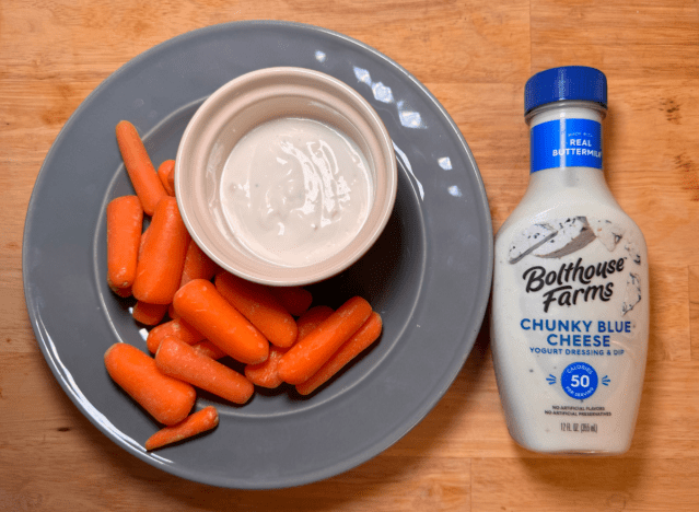 a bottle of blue cheese next to a plate of carrots 