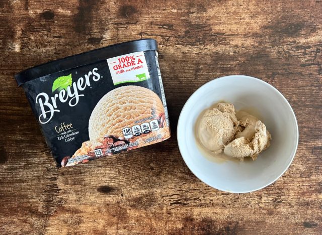 a container of breyer's coffee ice cream next to a bowl of breyers coffee ice cream on a wooden table