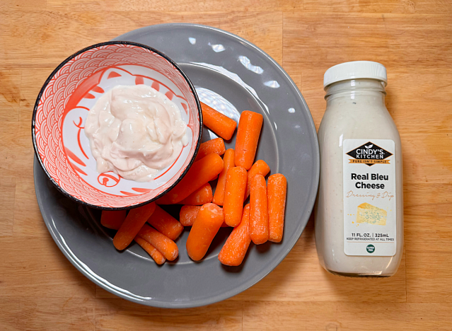 a bottle of cindy's blue cheese next to a plate of carrots 