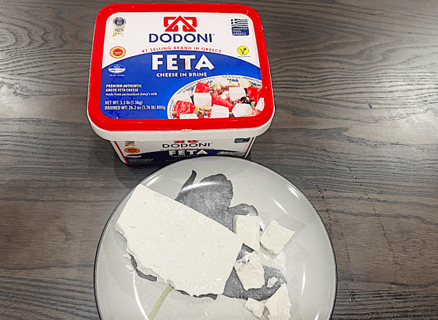 a container of dodoni feta cheese with some on a plate 
