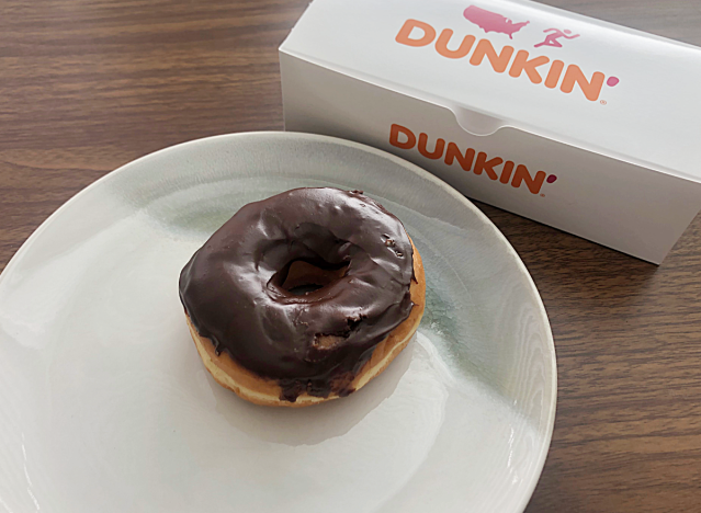a chocolate frosted donut from dunkin on a plate next to a box