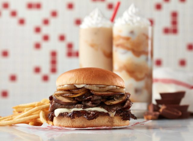 freddy's prime steakburger and fries over blurred background with reese's caramel peanut butter cup concrete and reese's creamy peanut butter shake