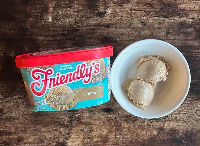 a container of friendly's coffee ice cream next to a bowl of coffee frozen dessert on a wooden table background