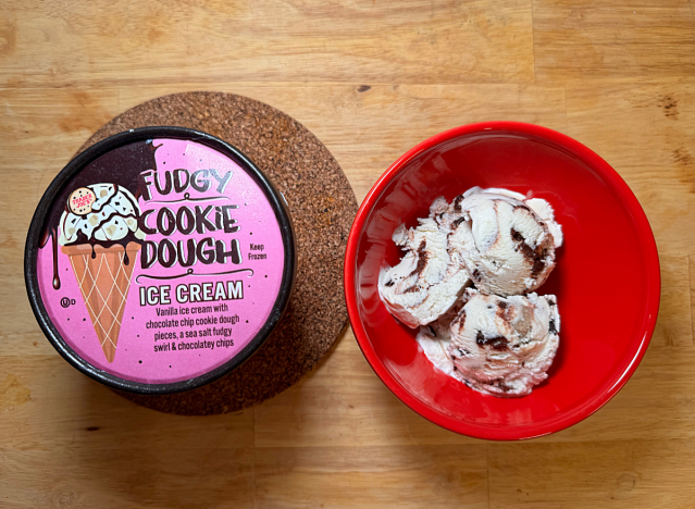 a container of trader joe's cookie dough ice cream next to a bowl of it 