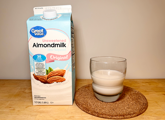 a container of great value almond milk next to a glass of it 