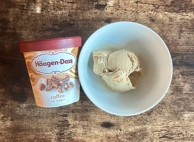 a container of häagen-dazs coffee ice cream next to a bowl of the ice cream on a wooden table background