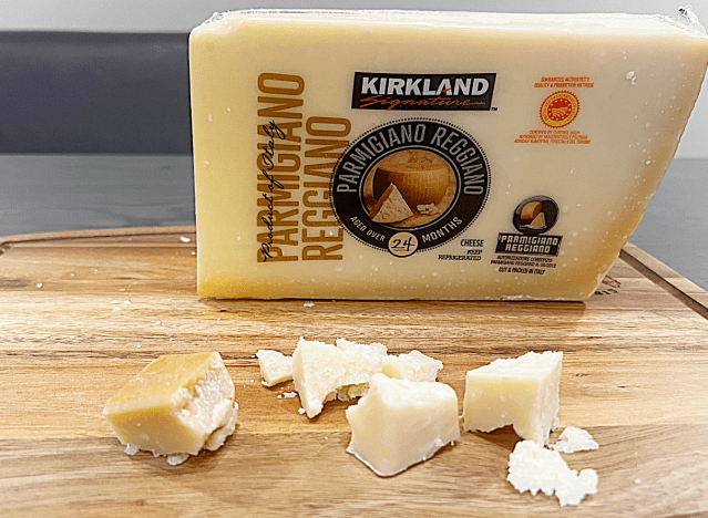 a block of kirkland parm reggiano cheese on a cutting board 