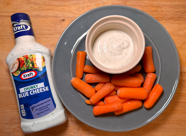 a bottle of kraft blue cheese next to a plate of carrots 