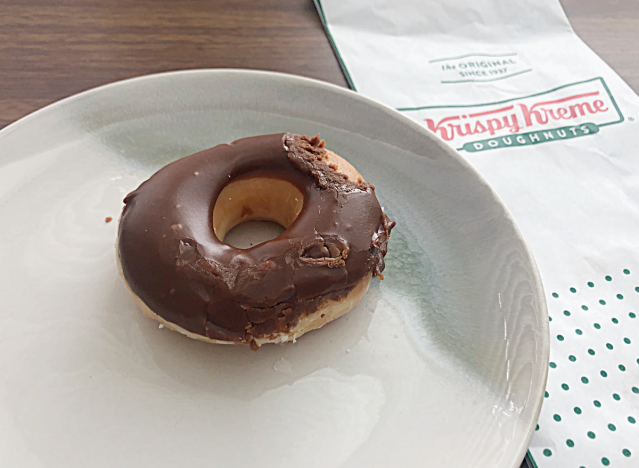 chocolate frosted donut from krispy kreme on a plate next to a bag 