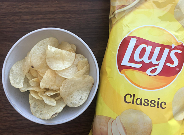 a bag of lays classic next to a bowl of chips