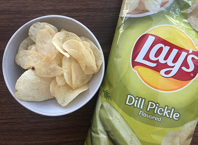 a bag of lays dill pickle next to a bowl of chips 