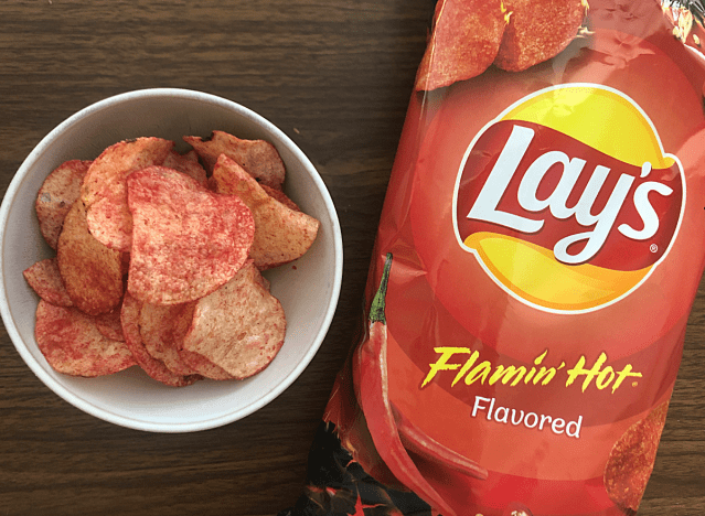 a bag of lays flamin hot next to a bowl of chips