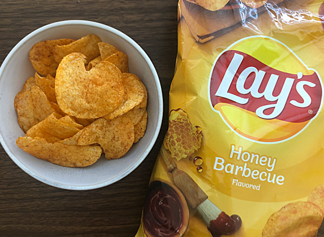 a bag of lays honey barbecue next to a bowl of chips