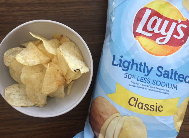 a bag of lays lightly salted next to a bowl of chips