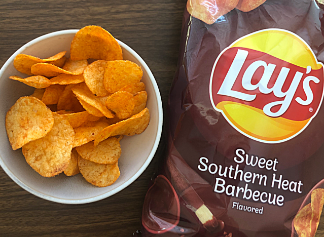 a bag of lays sweet southern heat bbq next to a bowl of chips